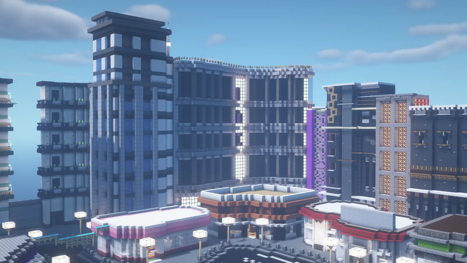 A Minecraft city built in blocks: tower blocks with glass fronts, lit shopfronts and street lamps along a plaza.